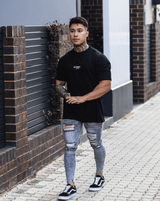 Man wearing grey ripped jeans and black t-shirt