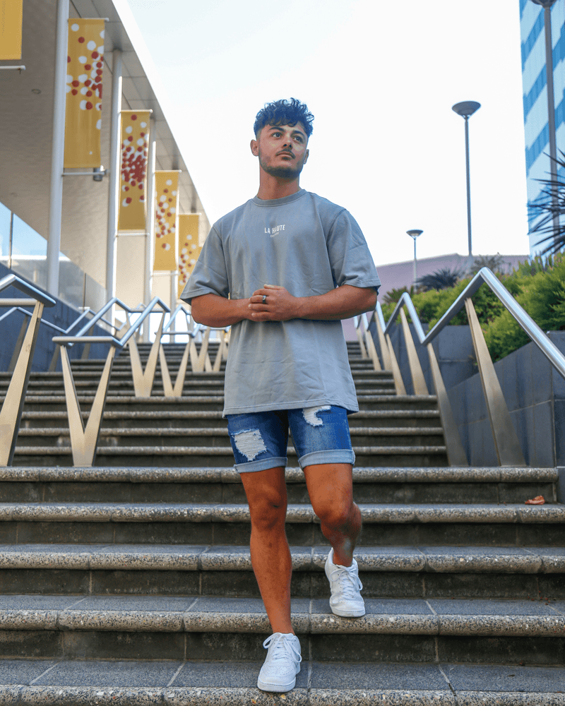 man walking down stairs in dark blue ripped shorts